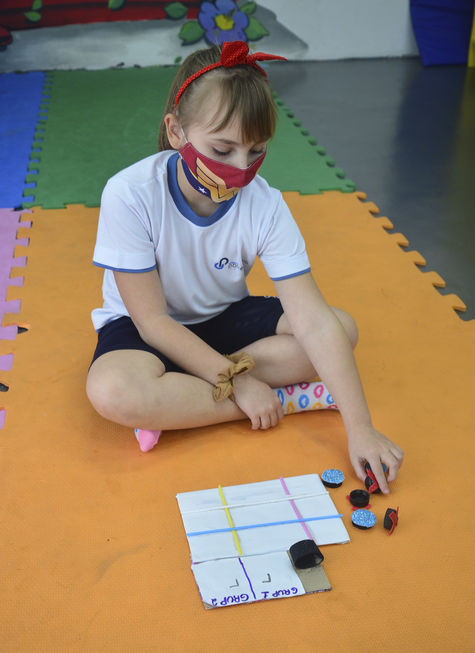 Jogo de damas com tampinhas e papelão.